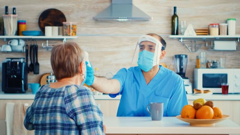 Caregiver with gun thermometer taking senior man